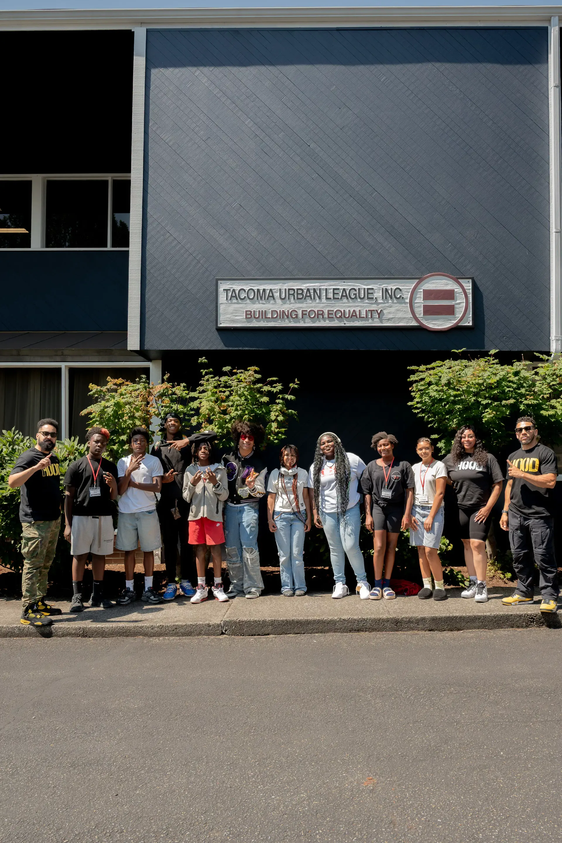 A diverse group of youth participants and staff stand outside the Tacoma Urban League building