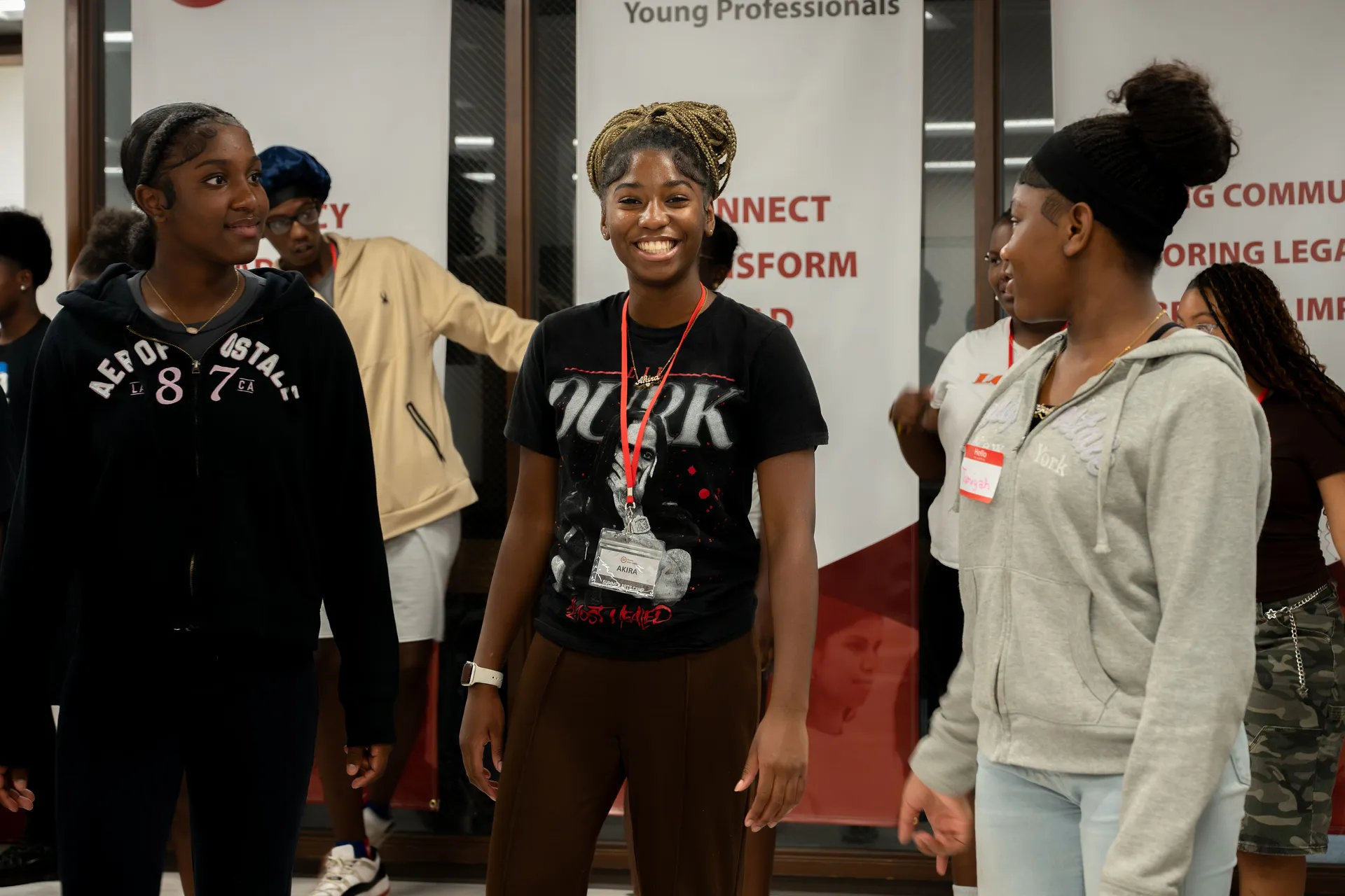 Young professionals in their 20s to 40s wear event lanyards at a Tacoma Urban League Young Professionals gathering with event signage behind them